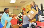 340th Flying Training Group volunteers (from left) Master Sgt. Faith Wells, Capt. Yolanda Seals and Lt. Col. Teresa Davies move boxes of clothing to the sorting area at the Family Violence Prevention Services/Battered Women and Children’s Shelter’s Donation Center during the group's Sept. 11 community outreach event.