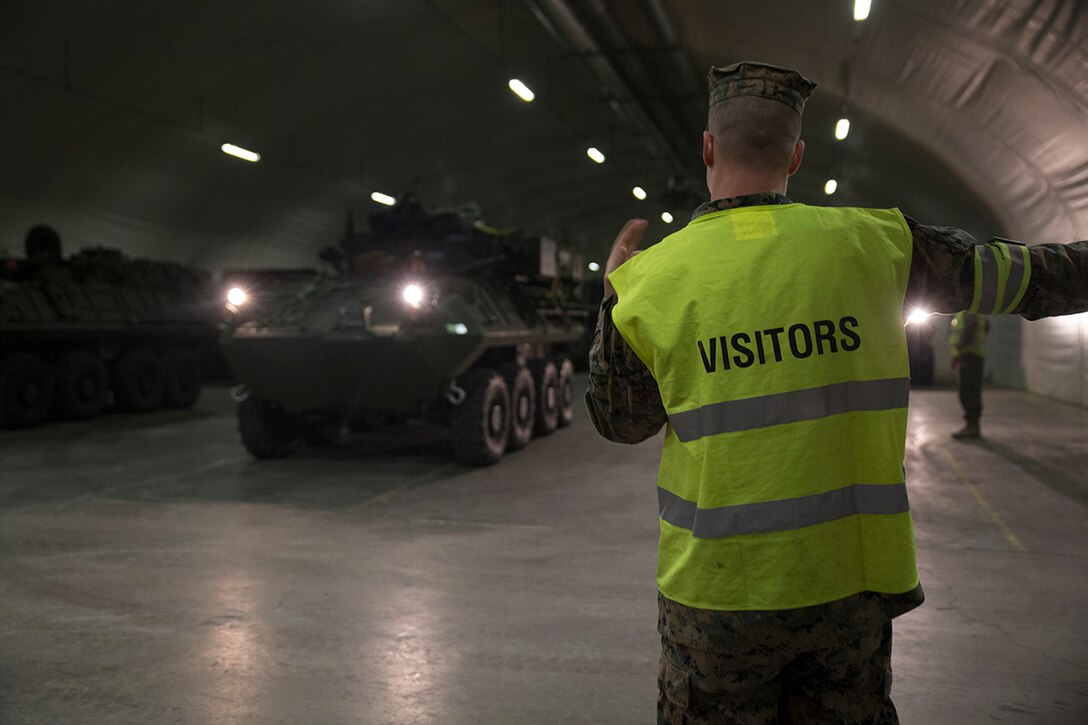 A U.S. Marine with 2nd Transport Support Battalion guides an LAV-25 Light Armored Vehicle out of a cave during an exercise in central Norway. DLA Disposition Services personnel recently visited underground storage sites there to assist with the removal and reuse of obsolete equipment.