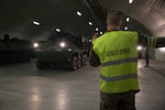 A U.S. Marine with 2nd Transport Support Battalion guides an LAV-25 Light Armored Vehicle out of a cave during an exercise in central Norway. DLA Disposition Services personnel recently visited underground storage sites there to assist with the removal and reuse of obsolete equipment.