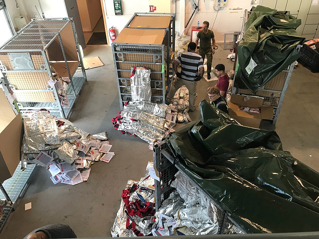 Disposal Services Representative Courtney Aubrey and Property Disposal Specialist Zeke Graham work alongside Norwegian personnel to prepare firefighting suits and other excess material for turn in to DLA at a secure storage facility in Norway.
