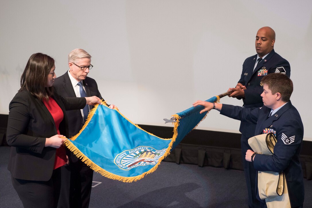 Kari A. Bingen, deputy under secretary of defense for intelligence, and others, unfurl a flag with three others