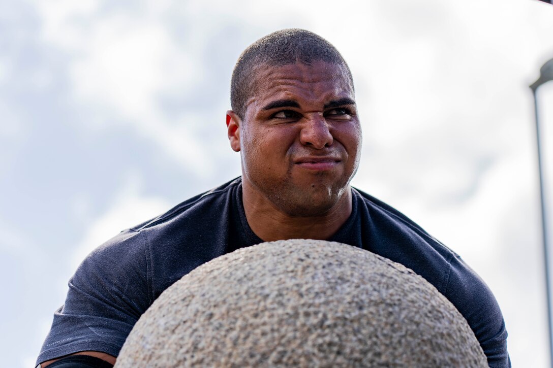 A Marine lifts a large circular stone.