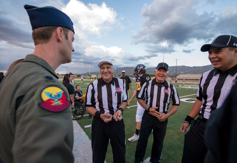 Lt. Col Ryan Typolt, 29th Attack Squadron commander, speaks with referees before an Alamogordo High School Military Appreciation Night football game, Sept. 27th, 2019, in Alamogordo, N.M. Typolt was invited to swear-in nine individuals into the Delayed Entry Program. (U.S. Air Force photo by Staff Sgt. Christine Groening)