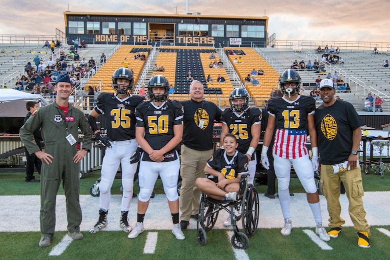 Lt. Col. Ryan Typolt (left), 29th Attack Squadron commander, poses with Alamogordo High School Football players and staff prior to an AHS Military Appreciation Night football game, Sept. 27th, 2019, in Alamogordo, N.M. Typolt was invited to swear-in nine individuals into the Delayed Entry Program. (U.S. Air Force photo by Staff Sgt. Christine Groening)