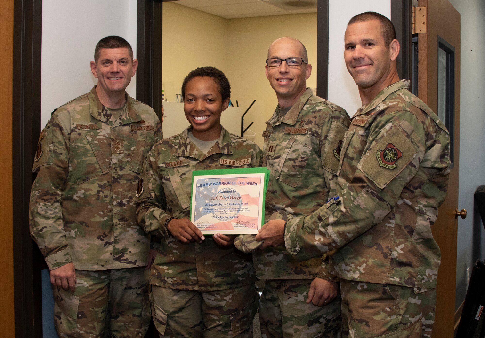 U.S. Air Force Col. Zachery Jiron, right, 60th Air Mobility Wing vice commander, Chief Master Sgt. Derek Crowder, left, 60th AMW command chief, and Capt. Kevin Hostettler, center right, 60th AMW Chapel chaplain recognize Airman 1st Class Kasen Hodges 60th AMW religious affairs journeyman, as the Warrior of the Week, Oct. 1, 2019 at Travis Air Force Base, California. The Warrior of the Week program recognizes an outstanding Travis Airman or noncommissioned officer. (U.S. Air Force photo by Heide Couch)
