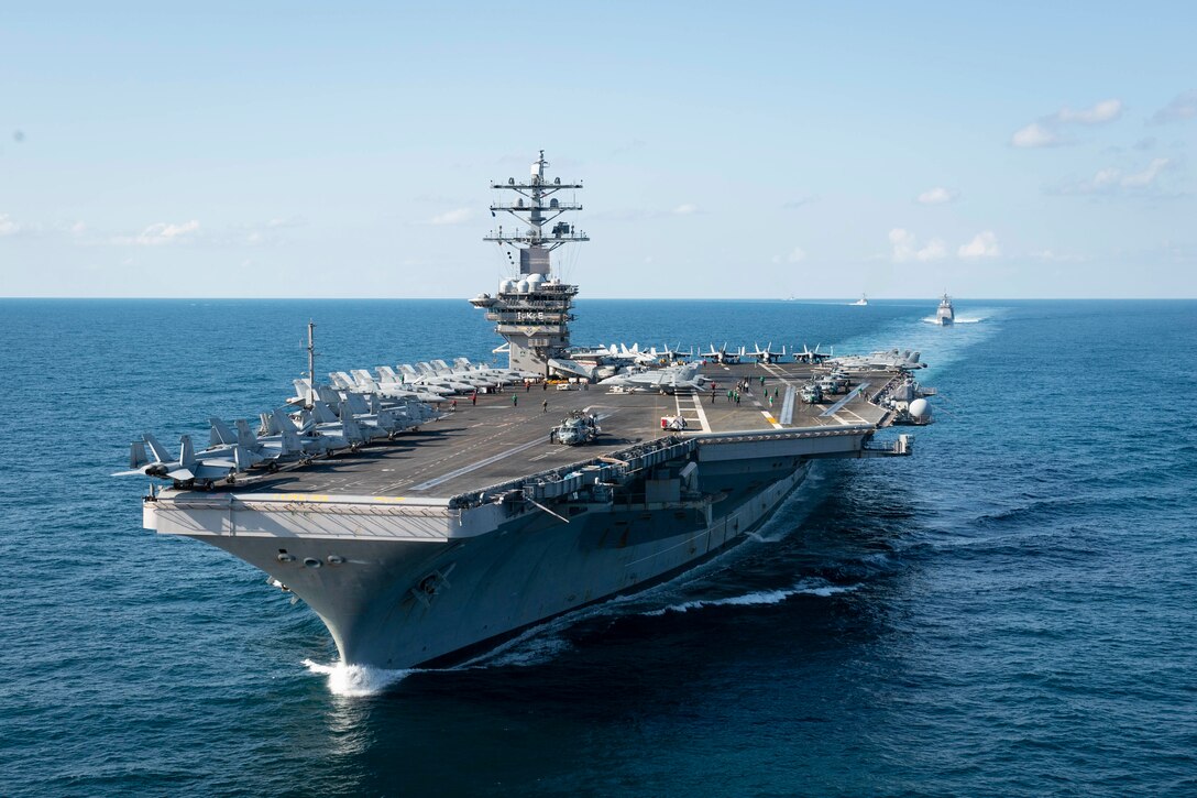 An aircraft carrier leads a group of other military ships in the Atlantic Ocean.