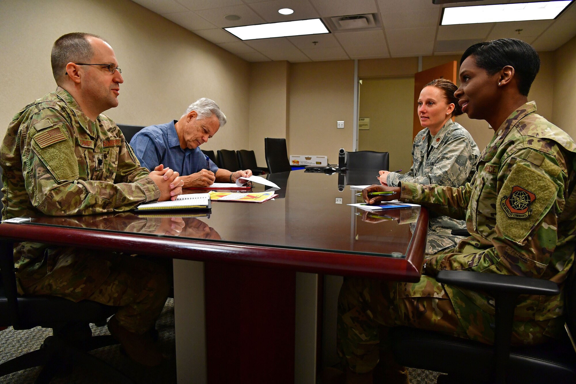 19th MDG Airmen conduct a meeting around a table.