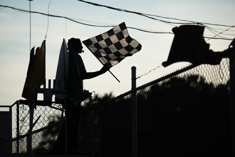 The Larry King Law's Langley Speedway flagman waves a checkered flag as a vehicle crosses the finish line during Military Appreciation Night at Langley Speedway, Hampton, Virginia, Sept. 28, 2019.