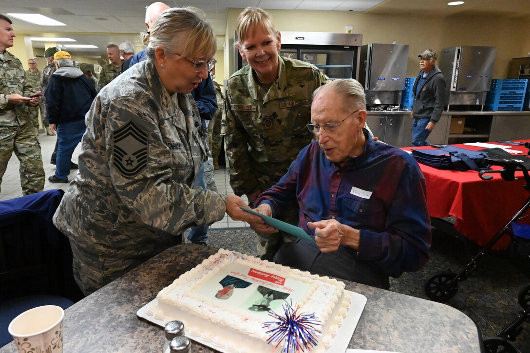 Chief Master Sgt. Val Buchholz, of the 119th Logistics Readiness Squadron, presents a birth card to retired Chief Master Sgt. Fred Quam in honor of his 103rd birthday during the annual 119th Wing Chief’s Council retiree breakfast at the North Dakota Air National Guard Base, Fargo, N.D., Oct. 2, 2019.