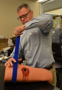 Dr. John Kragh, U.S. Army Institute of Surgical Research Department of Damage Control Resuscitation orthopedic surgeon and researcher, demonstrates the proper technique for packing a bleeding wound. Kragh is one of several Joint Base San Antonio-Fort Sam Houston trauma physicians, nurses and medics who are going to area schools to provide training to school personnel, including teachers and nurses, on the basics of treating a bleeding injury. A new state law that went into effect this year requires that school personnel and students be trained and prepared in the basics of treating an injury in the event of an emergency.