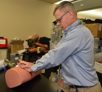 Dr. John Kragh, U.S. Army Institute of Surgical Research Department of Damage Control Resuscitation orthopedic surgeon and researcher, demonstrates the proper technique for packing a bleeding wound. Kragh is one of several Joint Base San Antonio-Fort Sam Houston trauma physicians, nurses and medics who are going to area schools to provide training to school personnel, including teachers and nurses, on the basics of treating a bleeding injury. A new state law that went into effect this year requires that school personnel and students be trained and prepared in the basics of treating an injury in the event of an emergency.