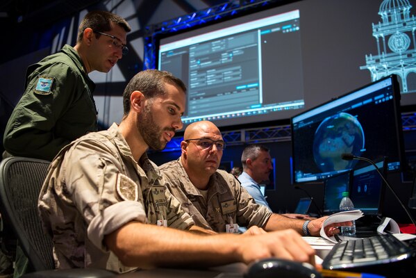 (From left) Brazilian Air Force Maj. Rafael de Almeida Duque, Brazilian Aerospace Command, collaborates with Spanish Air Force members at Lockheed Martin’s Center for Innovaton in Suffolk, Va., Sept. 27, 2019, during Global Sentinel 19. During the week, each participating nation maintained a space operations center (SpOC) to command and control their SSA space situational awareness.  (U.S. Air Force photo by Staff Sgt. J.T. Armstrong)