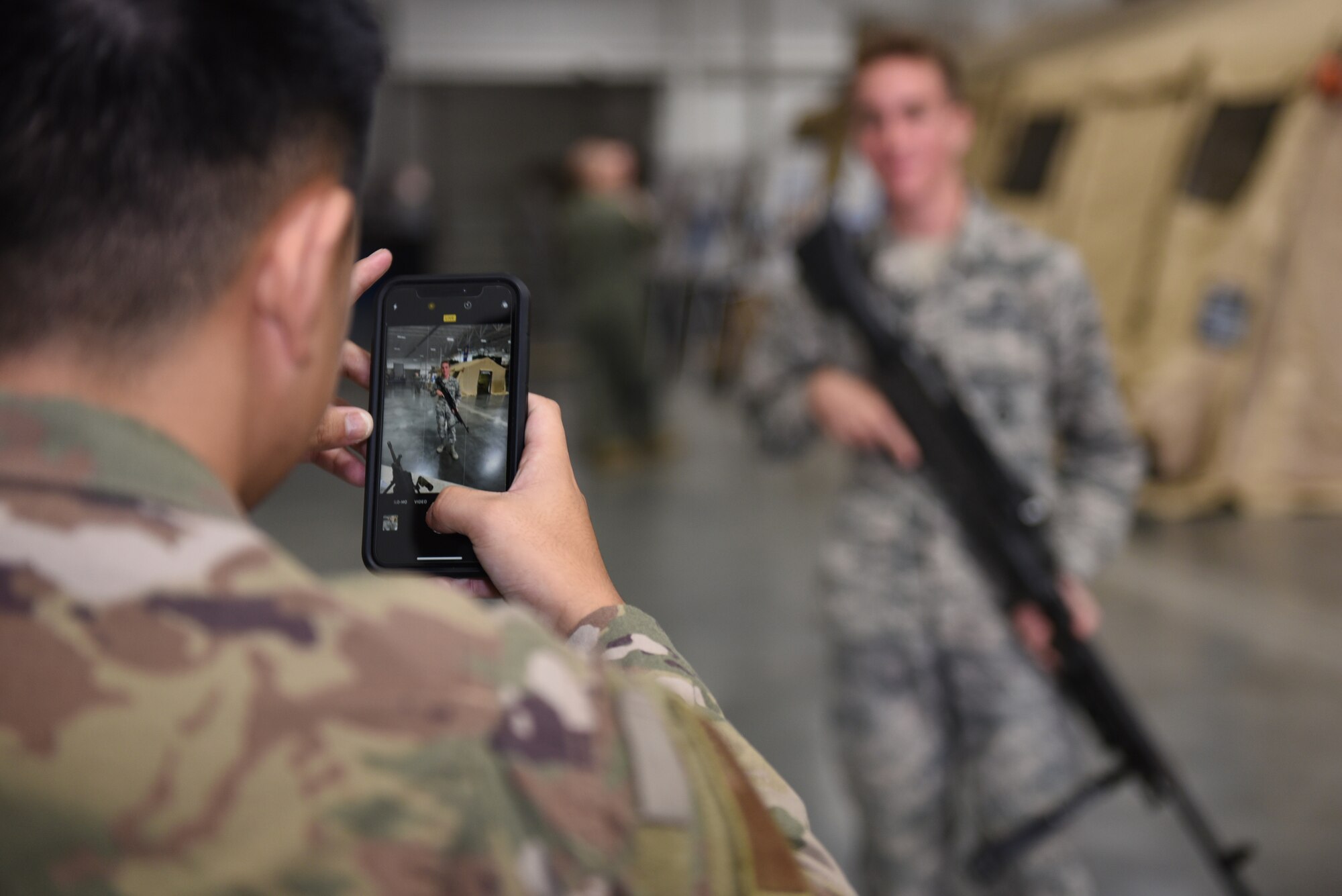 U.S. Air Force Airman 1st Class Brandon Pharn, 821st Contingency Response Squadron force protection team member, takes a photo of Airman Ezra Ashton, 60th Security Forces Squadron patrolman, holding an M-240B machine gun during the Airmen Enrichment Program Sept. 27, 2019, at Travis Air Force Base, California. The program offers Airmen the opportunity to learn about the numerous specialties the Air Force has to offer. (U.S. Air Force photo by Airman 1st Class Cameron Otte)