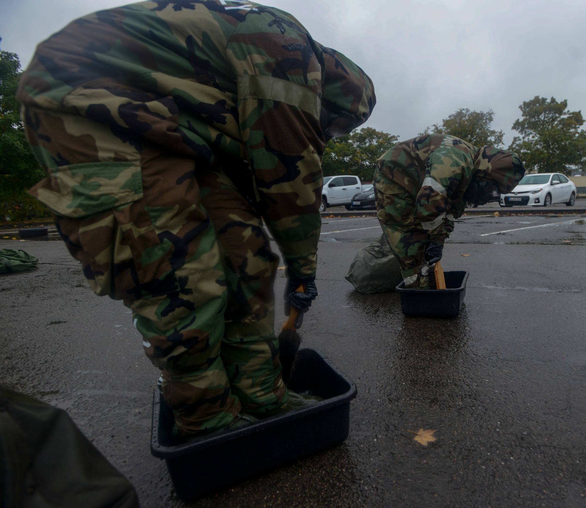 U.S. Airmen simulate scrubbing the boots of their mission-oriented protective posture gear as part of Operation Varsity 19-03 at Ramstein Air Base, Germany, Sept. 27, 2019. Airmen assigned to both the 86th Airlift Wing and 521st Air Mobility Operations Wing simulated decontaminating their equipment to become more familiar with the process. (U.S. Air Force photo by Tech. Sgt. Timothy Moore)