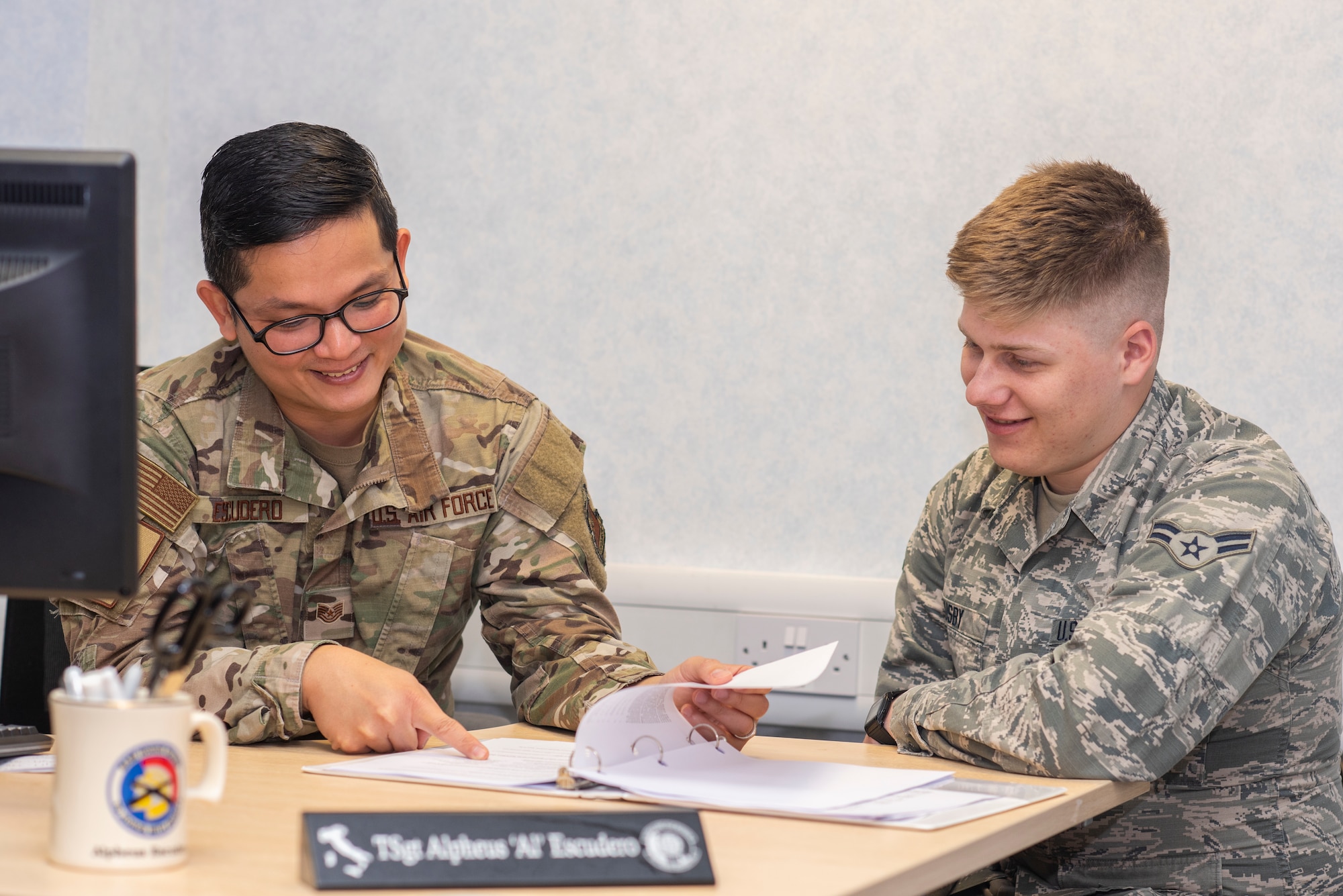 U.S. Air Force Tech. Sgt. Alpheus Escudero, 100th Force Support Squadron unit training manager, speaks with Airman 1st Class David Busby, 100th Air Refueling Wing broadcast journalist, about his Career Development Course volumes Oct. 1, 2019, at RAF Mildenhall, England. Unit training managers qualify Airmen to perform their jobs by tracking training requirements. (U.S. Air Force photo by Airman 1st Class Joseph Barron)