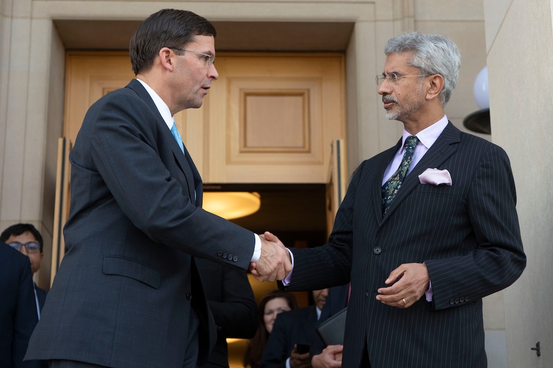 Two men shake hands at the entrance to the Pentagon.