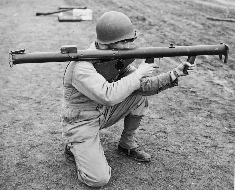A World War II Army infantry soldier holds a first-generation grenade launcher.