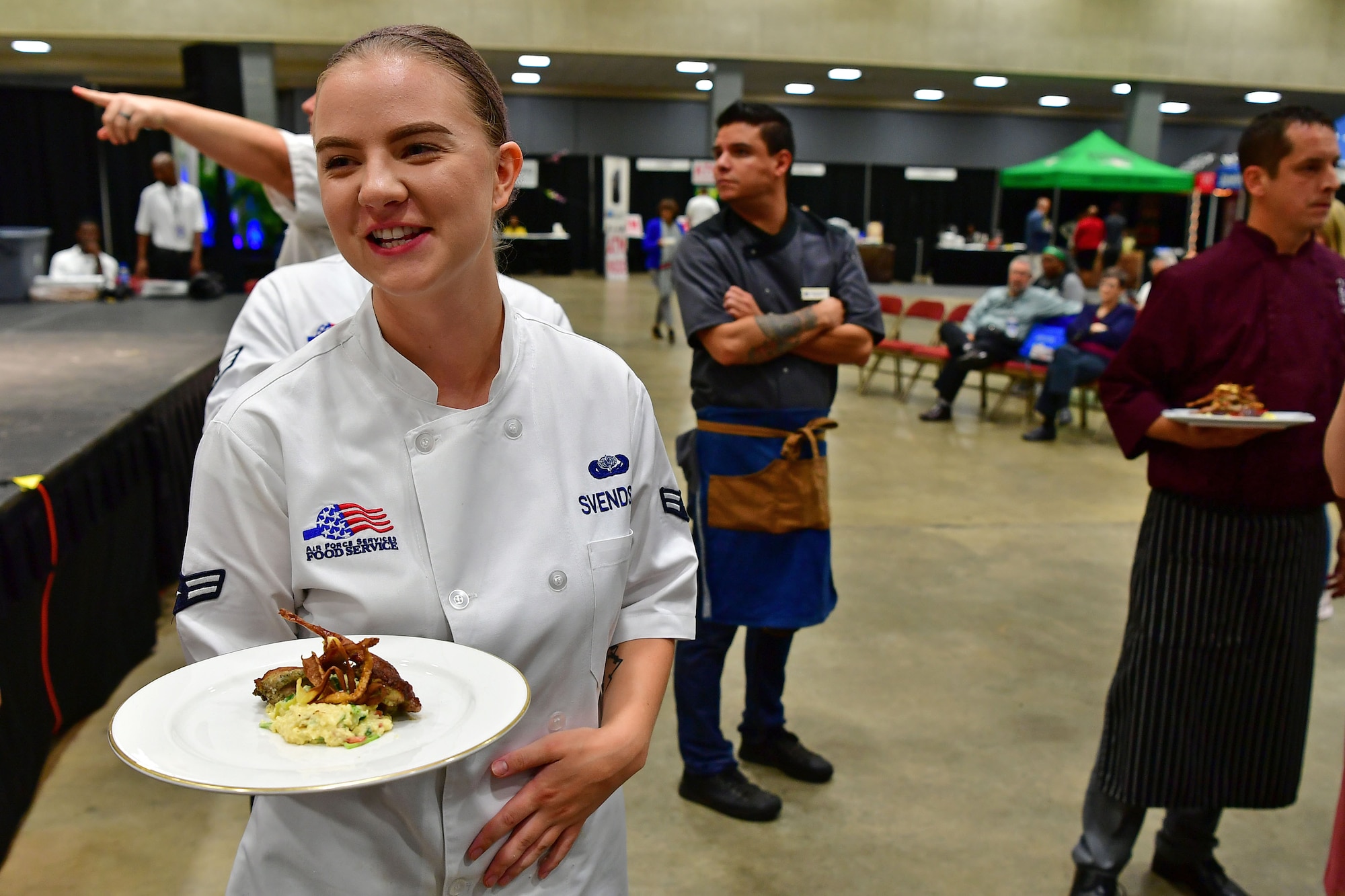 An Airman waits to hand her dish to the judges.