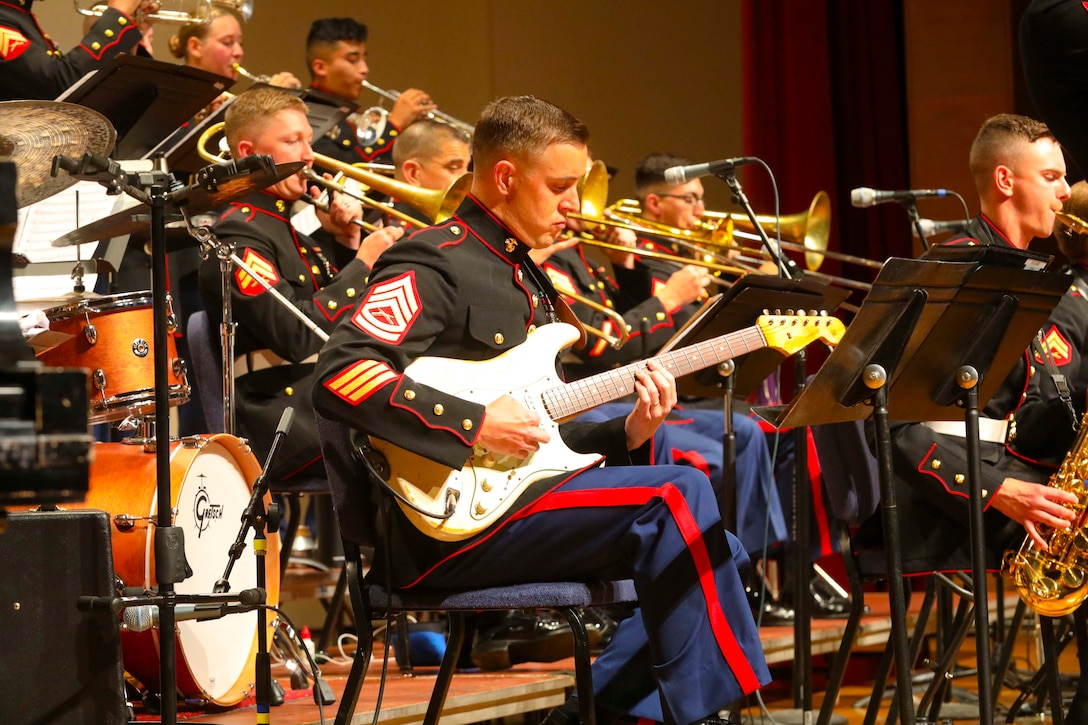 A group of Marines play instruments on a stage.