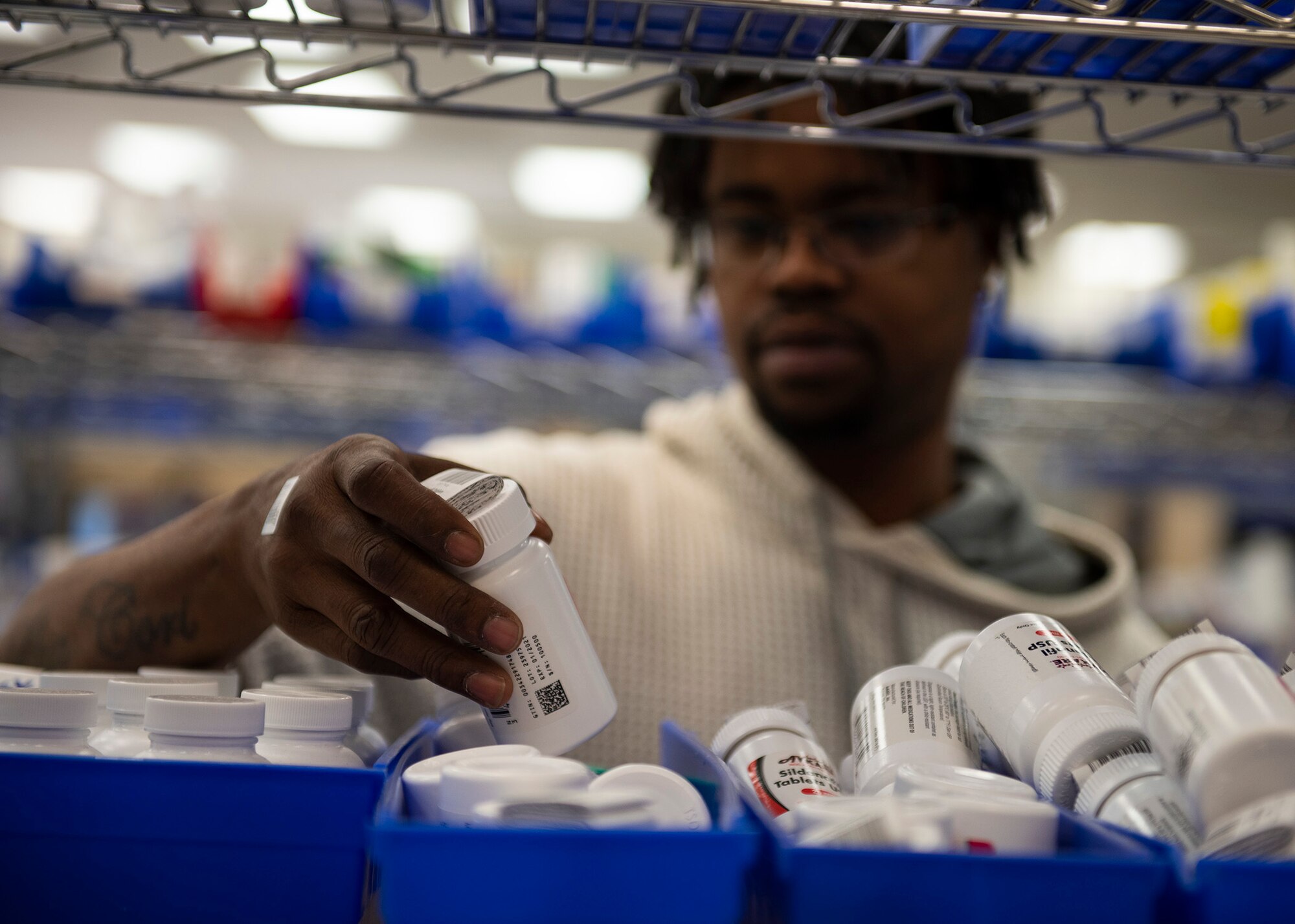 A pharmacy technician reaches a bottle of medication.