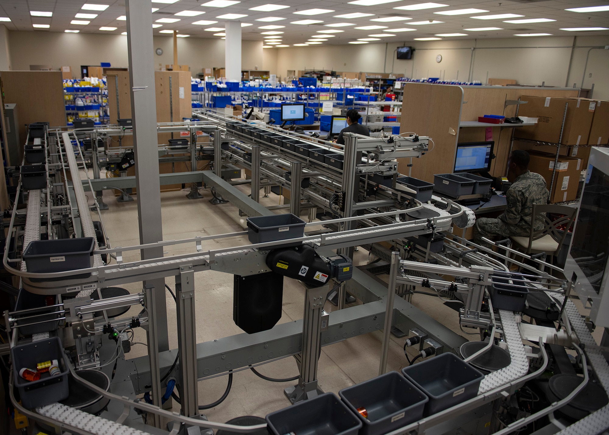 An overall view of the Satellite Pharmacy with a conveyor belt containing grey bins full of medication.