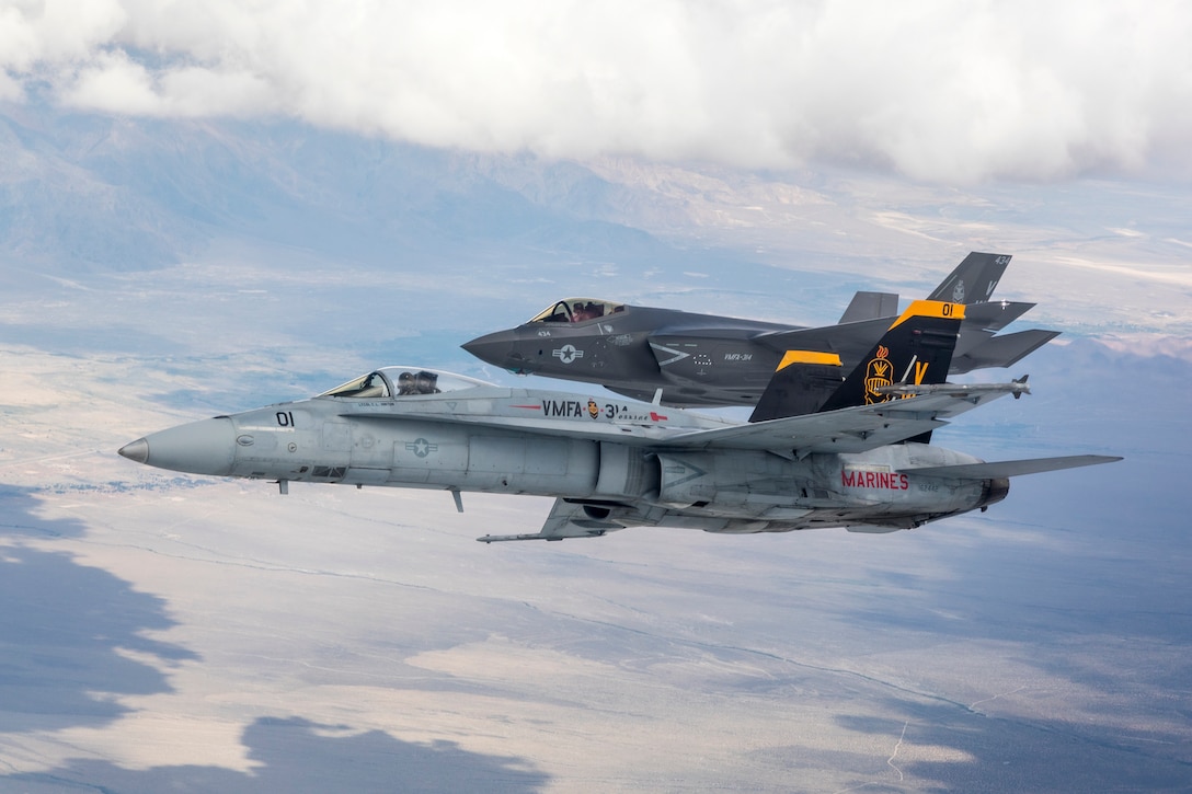 LEMOORE, California (June 5, 2019) The first Marine Fighter Attack Squadron (VMFA) 314 "Black Knights" F-35C aircraft from Naval Air Station (NAS) Lemoore flown by CAPT Tommy Beau Locke from Strike Fighter Squadron (VFA) 125 "Rough Raiders" flies in formation over the Sierra's with the VFMA-314 squadron F/A-18A++, flown by LtCol Cedar Hinton aircraft  "passing the lead" as part of the F/A-18 Sundown with the Black Knights.  (U.S. Navy photo by Lt. Cmdr. Darin Russell/Released)