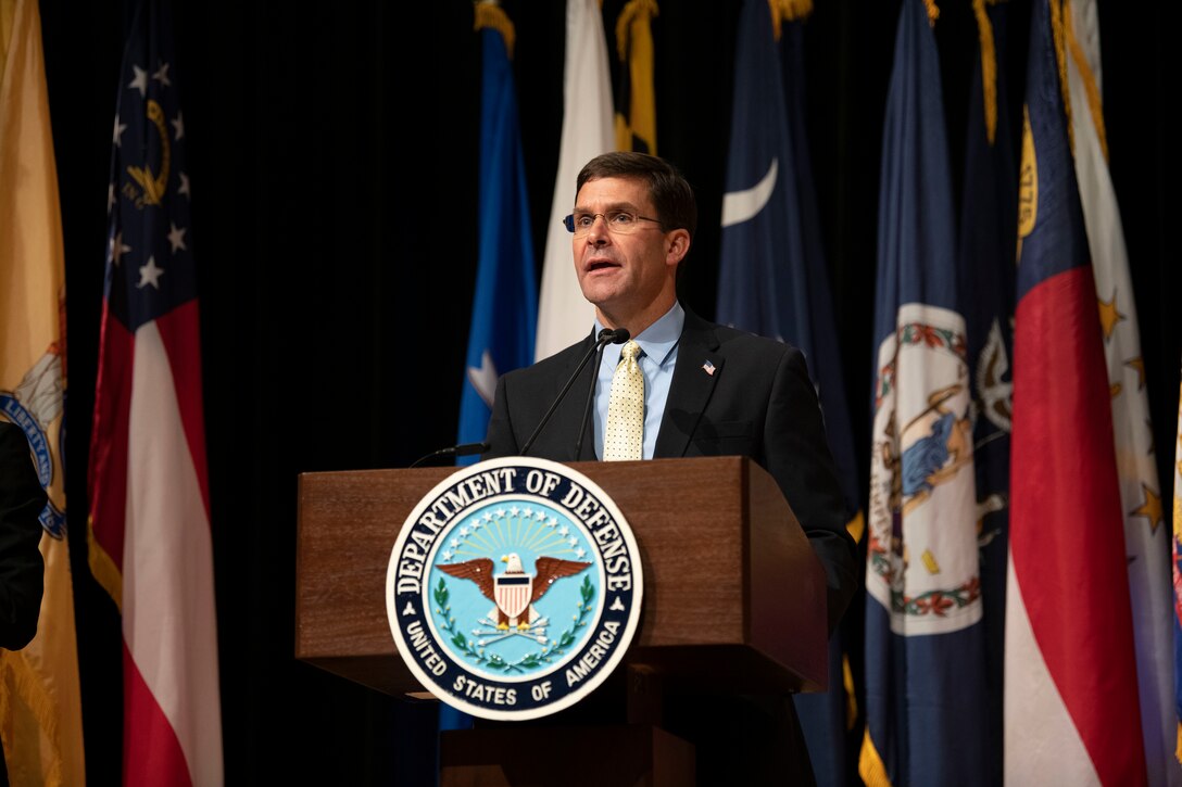 Man speaks at lectern that bears the Defense Department emblem.