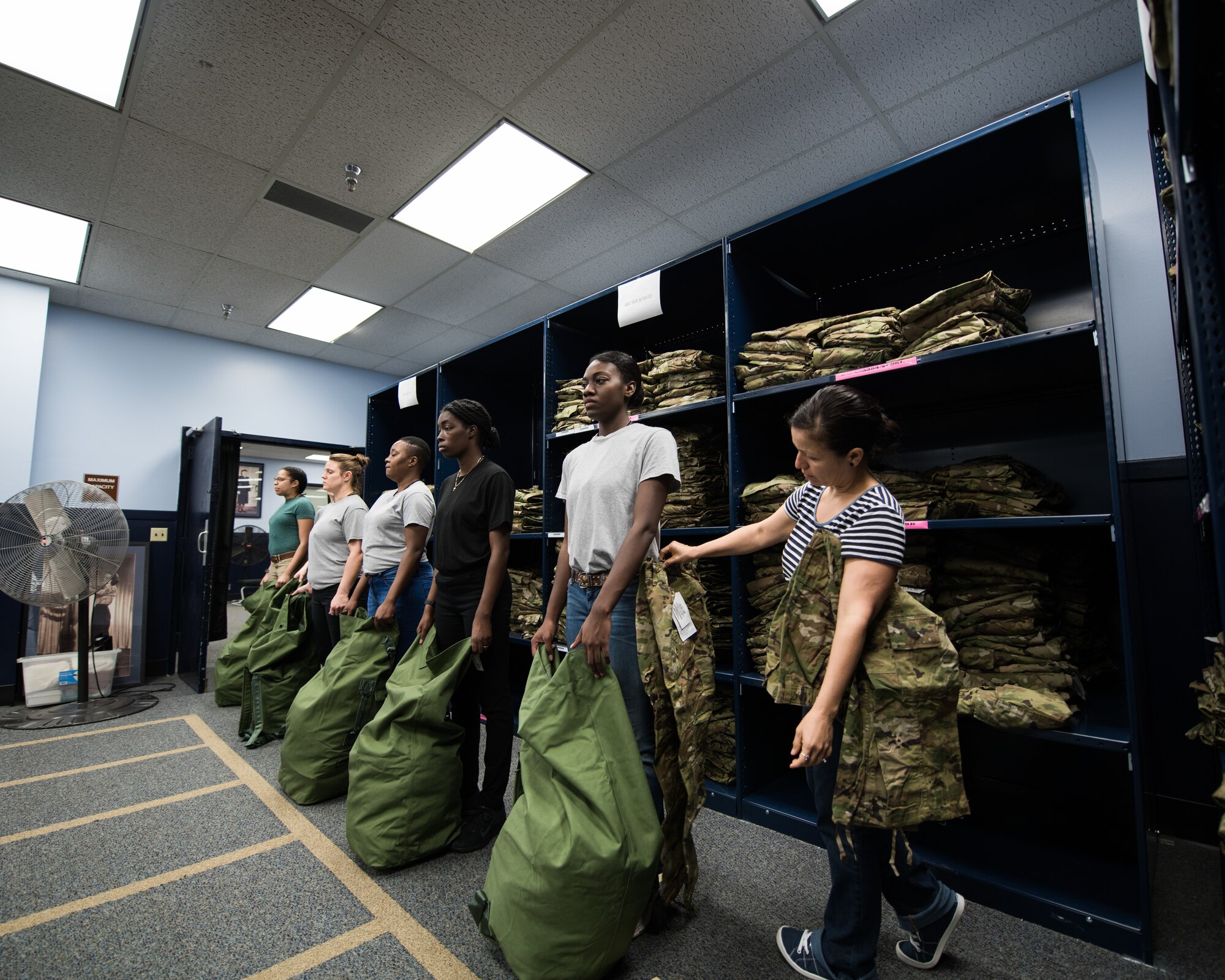 Cecil Harvey, 502d Logistics Readiness Squadron lead supply technician, helps a U.S. Air Force basic military training trainee, 326th Training Squadron, during the initial issue of the first operational camouflage pattern (OCP) uniform, Oct. 2, 2019, at Joint Base San Antonio-Lackland, Texas.