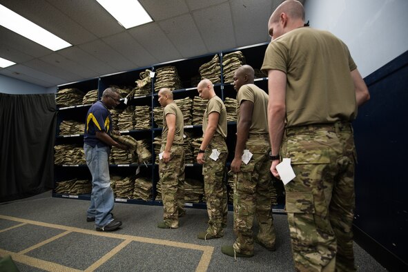 Cecil Harvey, 502d Logistics Readiness Squadron lead supply technician, helps a U.S. Air Force basic military training trainee, 326th Training Squadron, during the initial issue of the first operational camouflage pattern (OCP) uniform, Oct. 2, 2019, at Joint Base San Antonio-Lackland, Texas.