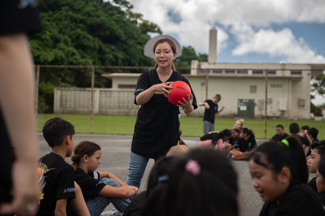 Yuko Kakazu, 18th Force Support Squadron child development program assistant, explains the rules of Japanese dodgeball to children during Cultural Exchange Day, Sept. 28, 2019, at Kadena Air Base, Japan. The rules of Japanese dodgeball are similar to American dodgeball, however, in Japanese dodgeball once a player is out, other players can move around boundary lines and attempt to hit the remaining players with balls. (U.S. Air Force photo by Staff Sgt. Micaiah Anthony)