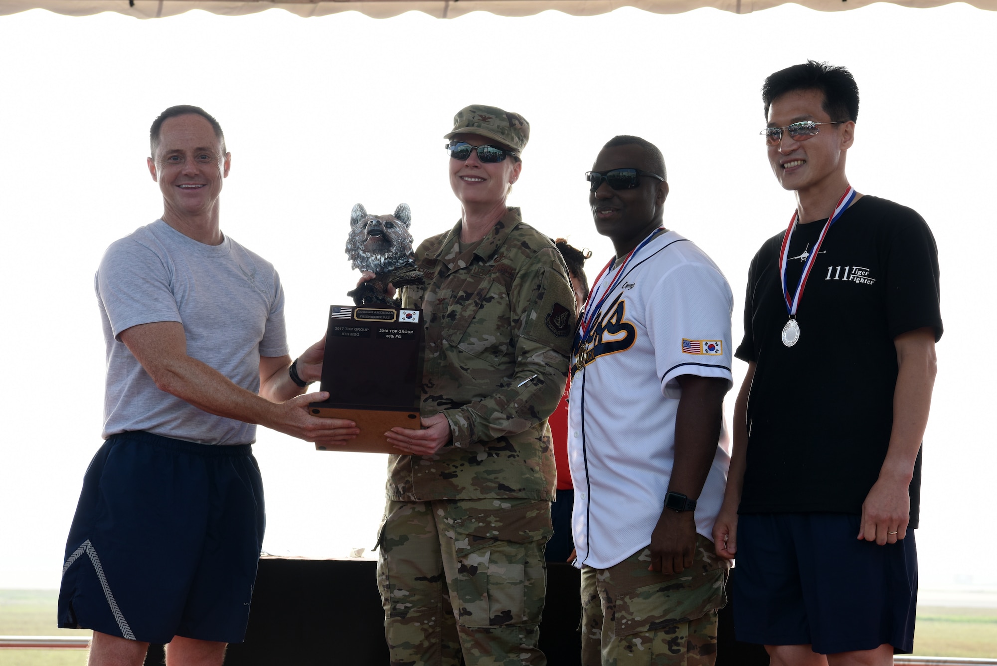 (Left) U.S. Air Force Col. Tad Clark, 8th Fighter Wing commander, and (right) Republic of Korea Air Force Col. Keun-Shin Kang, 38th Fighter Group commander, provide U.S. Air Force Col. Jennifer Nevius, 8th Mission Support Group commander, and Chief Master Sgt. Craig Brodber, 8th MSG superintendent, with a trophy after 8th MSG won overall during Friendship Day at Kunsan Air Base, Republic of Korea, Oct. 4, 2019. Throughout the day U.S. and ROK competed in nine different events to determine an overall winner. (U.S. Air Force photo by Staff Sgt. Joshua Edwards)