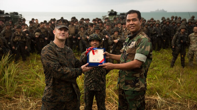 U.S. Marine Lt. Col. Todd Jacobs, the Commander of Toops for 3rd Marine Division during exercise Tiger Strike 19, presents a gift to the Malaysian Armed Forces at Blue Beach, Malaysia, on Oct. 2, 2019. Tiger Strike 19 focuses on strengthening joint military interoperability and on increasing readiness by practicing for humanitarian assistance, disaster relief, amphibious and jungle warfare operations, all while fostering cultural exchanges between the MAF and the U.S. Navy, Marine Corps team. (U.S. Marine Corps photo by Cpl. Josue Marquez)