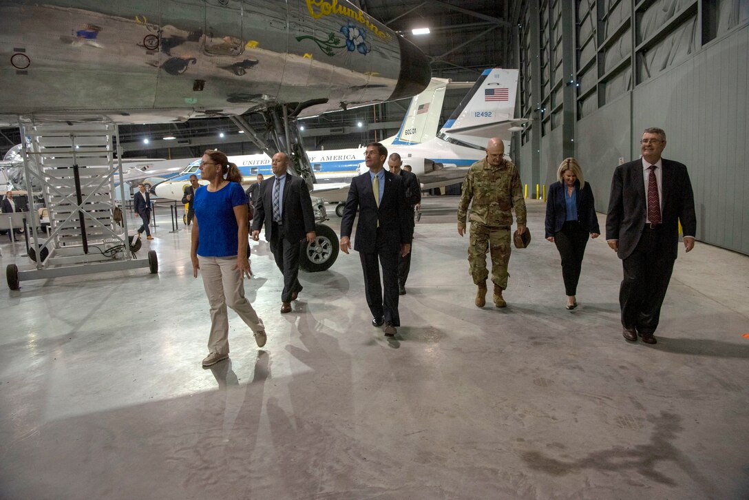 A group of people walk together in a large hangar.