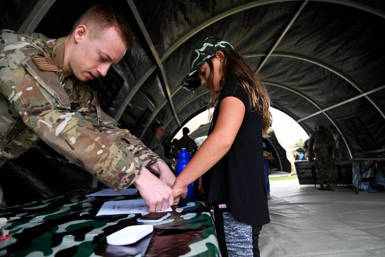 Senior Airman Bradley Skinner, 22nd Security Forces Squadron installation patrolman, assists children with fingerprinting during the family mobility line event Sept 28, 2019 at McConnell Air Force Base, Kan. The event has been held every year since 2001 by the Airman and Family Readiness Center. The family mobility line introduces and educates families on the mission of McConnell and gives children the opportunity to learn about the mobility process. (U.S. Air Force photo by Airman 1st Class Nilsa E. Garcia)