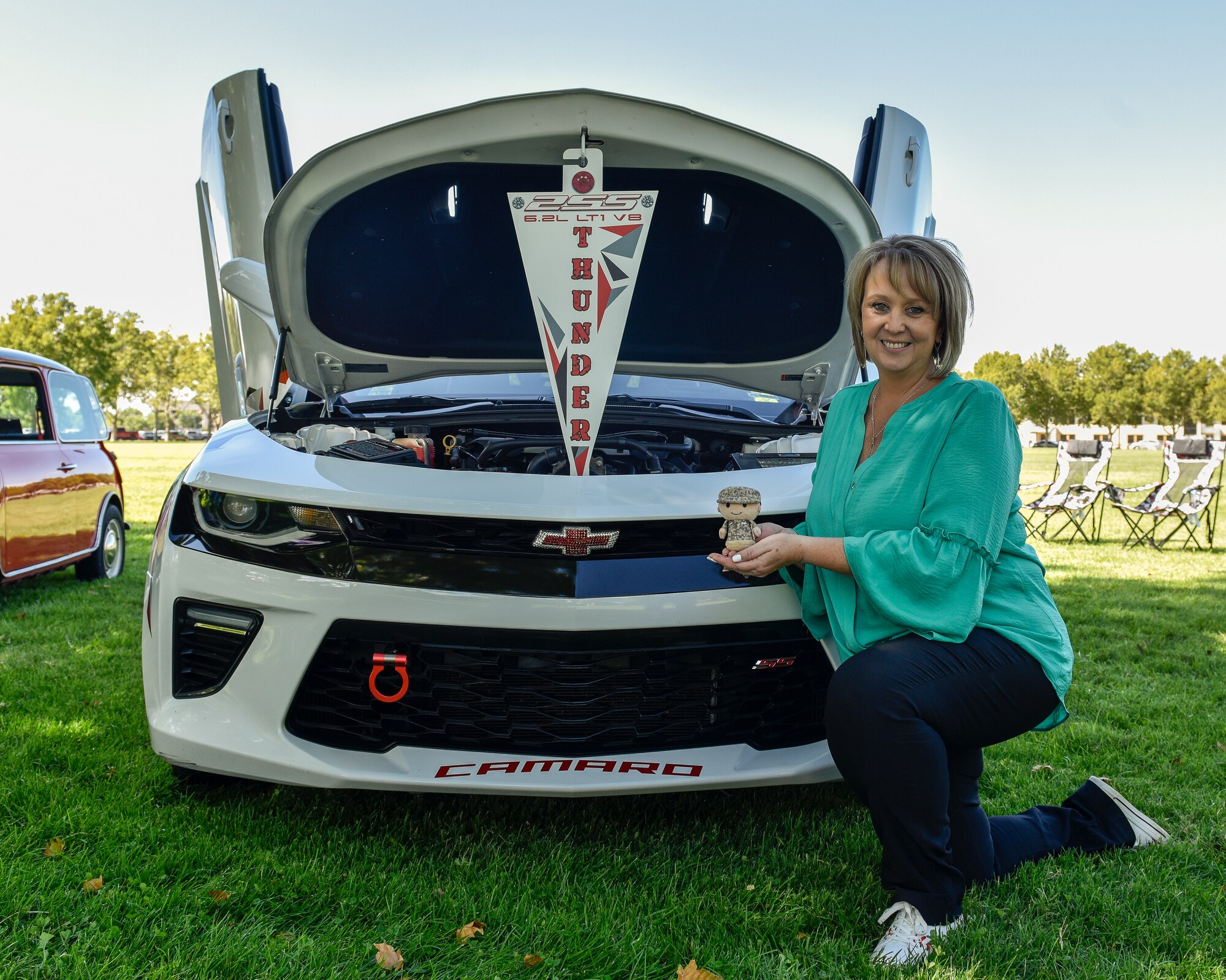 Renate Schuler, participant in the Hispanic Heritage Month festival car show, poses for a photo next to her car ‘Thunder’ at Kirtland Air Force Base, N.M., Oct. 3, 2019. Schuler’s doll dressed in uniform represents her son who is currently serving in the U.S Air Force. (U.S. Air Force photo by Airman 1st Class Austin J. Prisbrey)