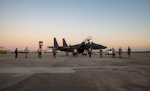 Ten Airmen walk towards an aircraft on the flight line.