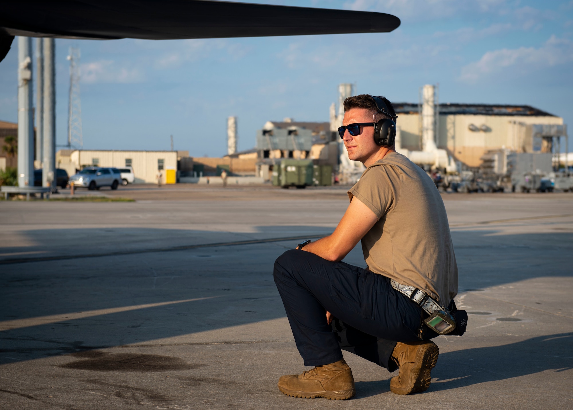 An Airman kneels down on the flight line.