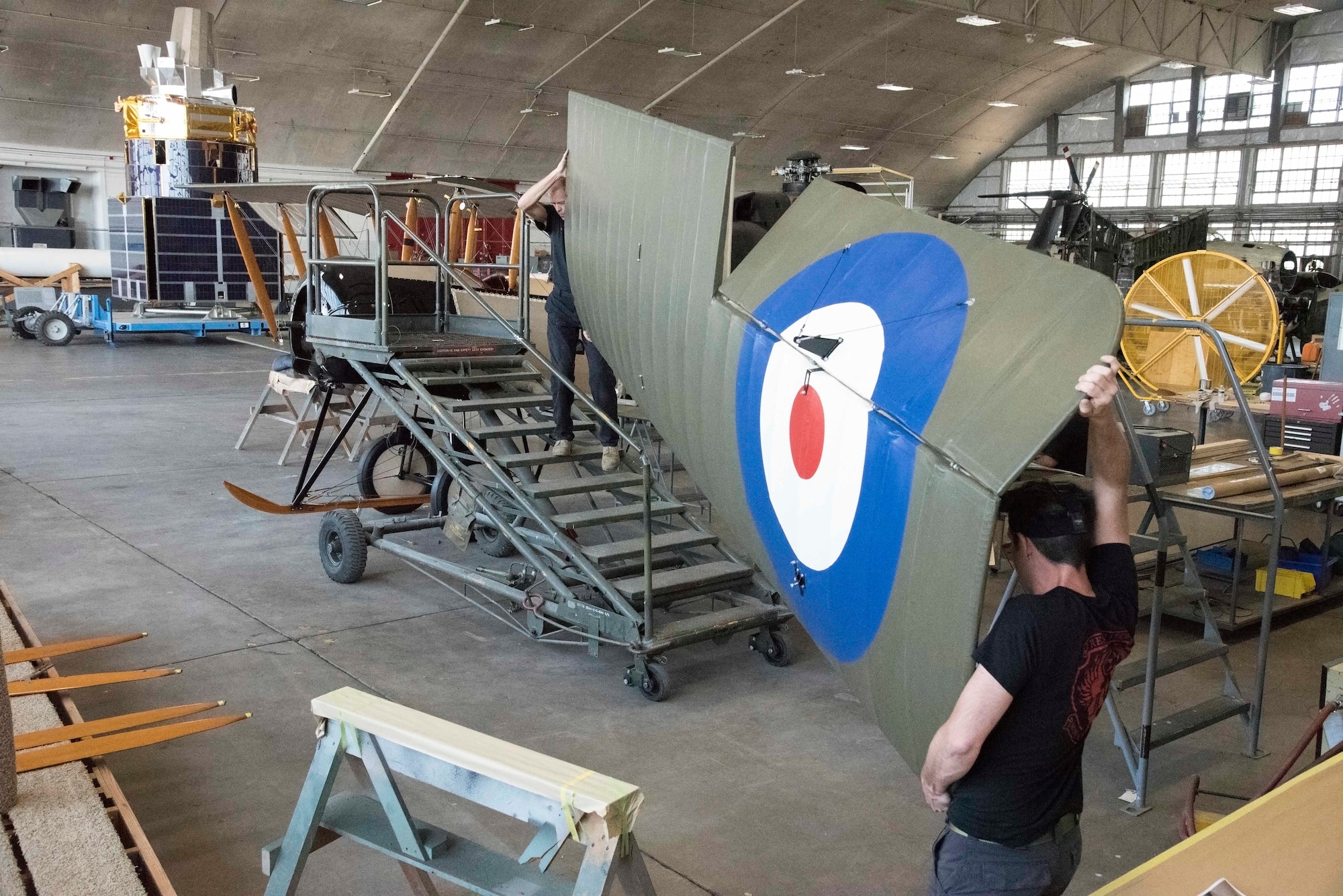 Restoration crew members working on biplane wing during restoration.