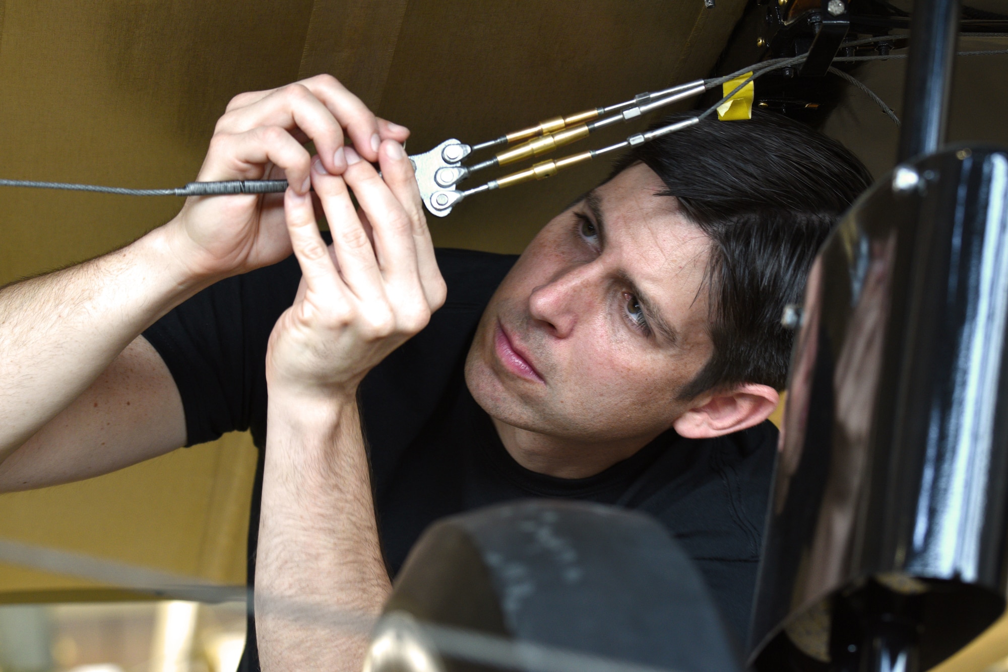 Restoration crew member working on biplane turnbuckle during restoration.