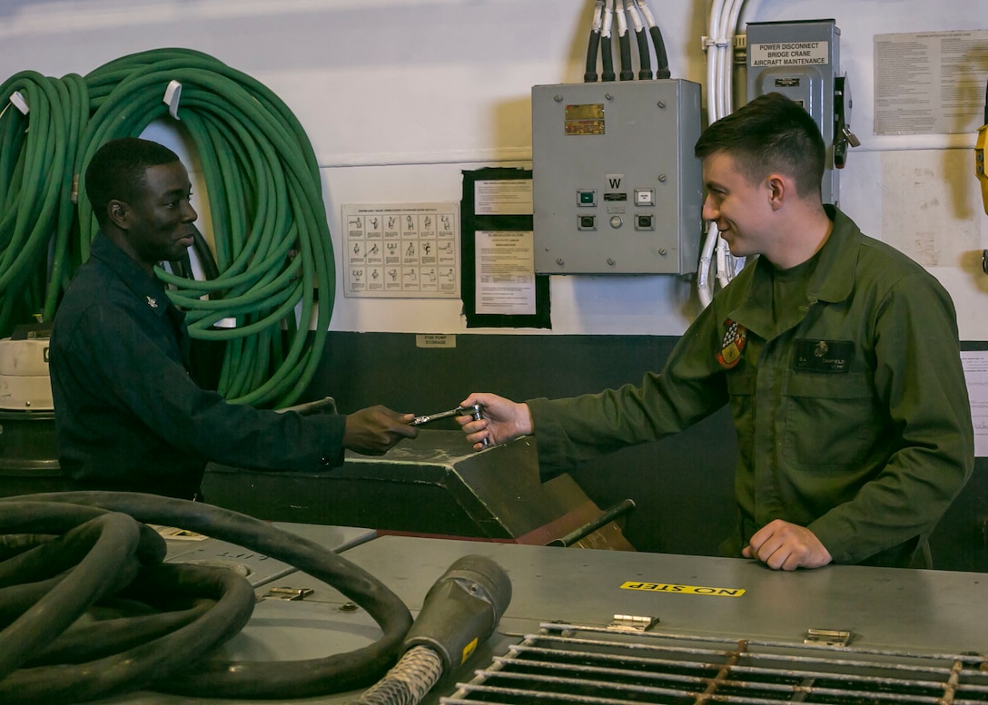 U.S. Navy Petty Officer 2nd Class Halin Arilus, aviation support technician with USS America, left, and U.S. Marine Corps Lance Cpl. Dustin Canfield, aircraft support equipment technician with Marine Aviation Logistics Squadron (MALS) 13, Marine Aircraft Group (MAG) 13, 3rd Marine Aircraft Wing (MAW), perform maintenance on an electric polyalphaolefin servicing cart aboard the amphibious assault ship USS America (LHA 6) Sept. 30, 2019. America is underway conducting routine operations in the Eastern Pacific. (U.S. Marine Corps photo by Lance Cpl. Juan Anaya)