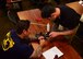U.S. Air Force Staff Sgt. Travis Holmes, 68th Rescue Squadron air operations instructor, shows a student how to use a piece of equipment during the Guardian Angel Military Freefall Jumpmaster Course at Davis-Monthan Air Force Base, Arizona, Sept. 27, 2019. This course is accredited by the United States Department of Defense Special Operations Command and is one of only four in the entire DoD. (U.S. Air Force photo by Airman 1st Class Jacob T. Stephens)