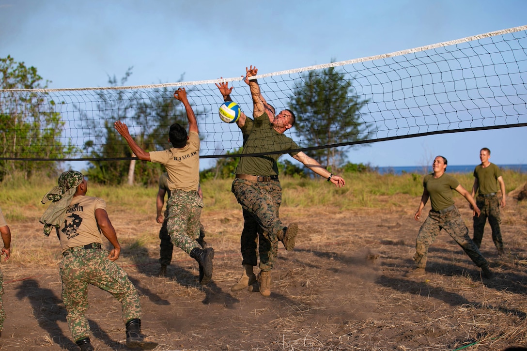 A group of U.S. and Malaysian service members play beach volleyball.