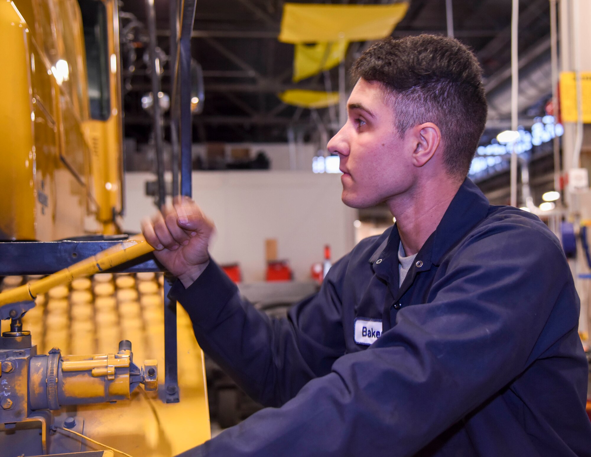 U.S. Air Force Airman Nathaniel Baker, 92nd Logistics Readiness Squadron vehicle maintainer, pumps the handle on an Oshkosh broom sweeper vehicle that opens the rear engine cover