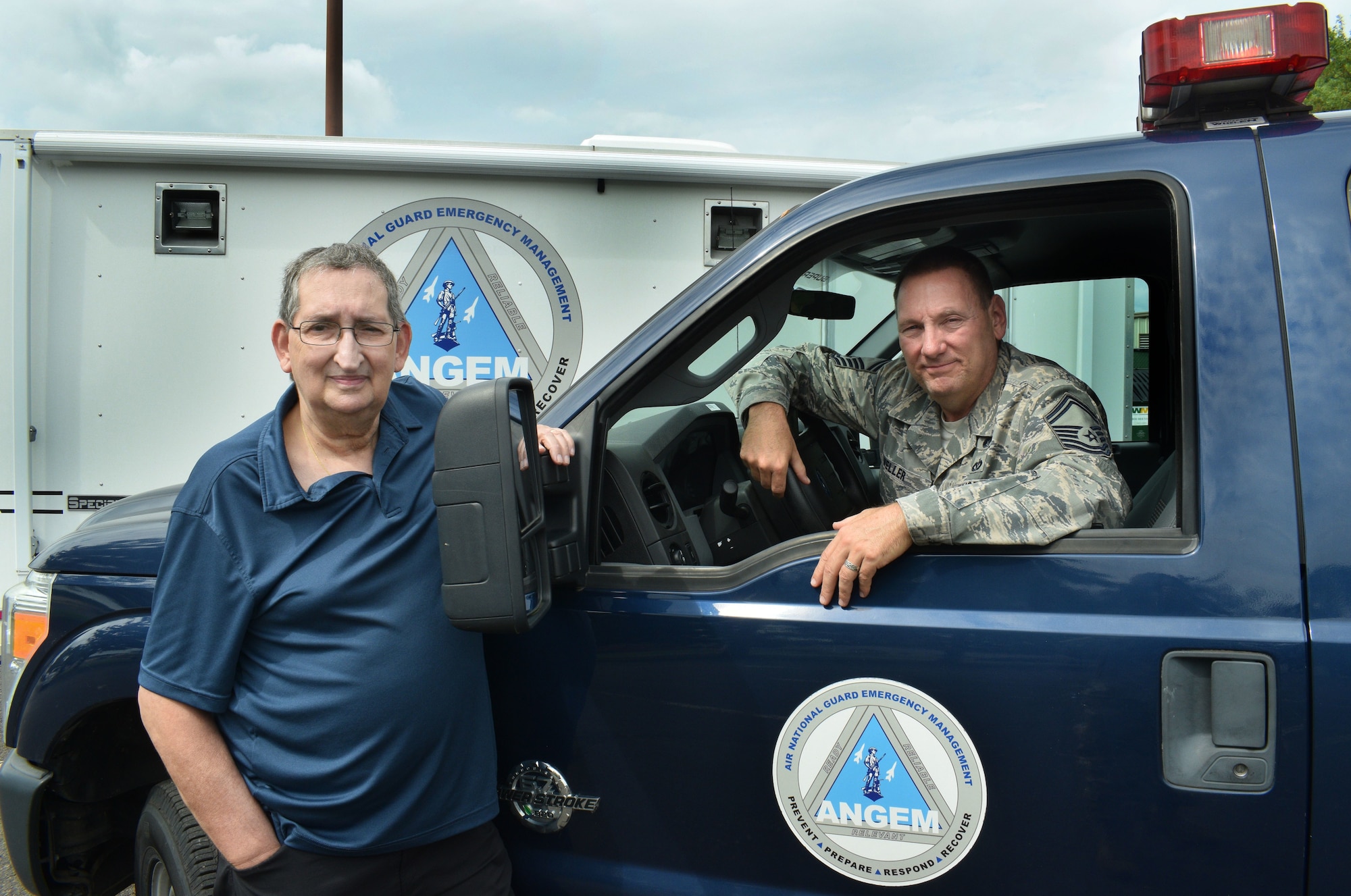 Picture of two men, one is in a blue truck.