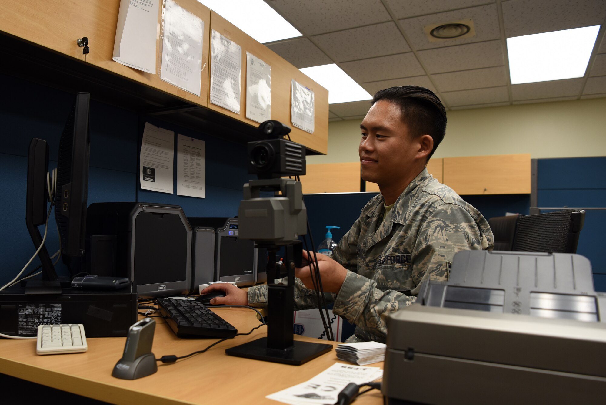 U.S. Air Force Staff Sgt. Daniel Ly, 8th Force Support Squadron customer support noncommissioned officer in charge, adjust a camera on his desk at Kunsan Air Base, Republic of Korea, Oct. 1, 2019. When Ly is not assisting customers with getting new common access cards and enrolling in the Korea Area Incentive Program, he likes to run to relieve his stress and stay in shape. (U.S. Air Force photo by Staff Sgt. Joshua Edwards)