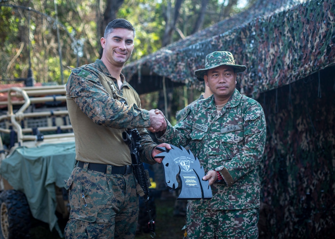 A U.S. Marine gives a plaque to a member of the Malaysian Armed Forces, Oct. 4.