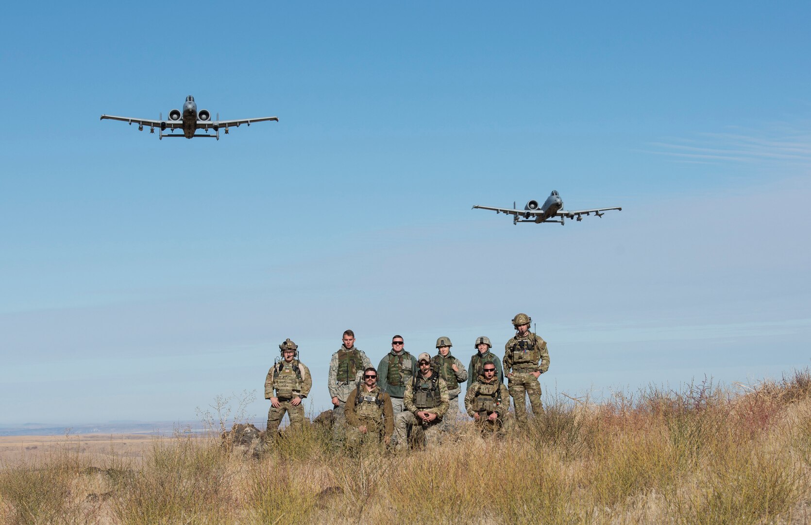 A pair of A-10 Thunderbolt IIs assigned to the 190th Fighter Squadron flies over a group of Airmen from the 124th Fighter Wing at the Saylor Creek Bombing Range, Idaho, Oct. 5, 2019. The range provides a designated area for pilots, Tactical Air Control Party Airmen and other mission-essential groups to run training missions.