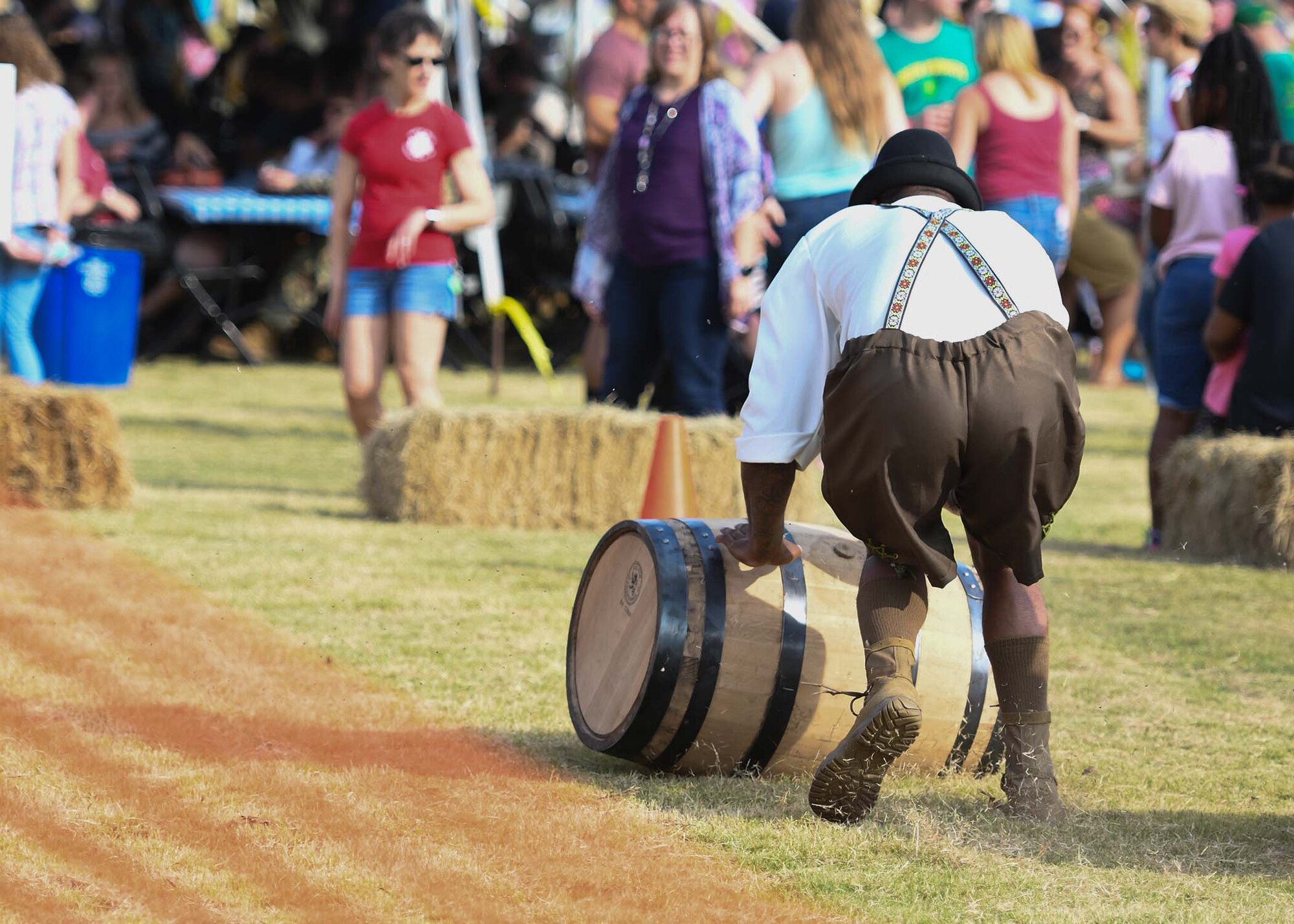 A guy rolls a barrel across the grass during Oktoberfest