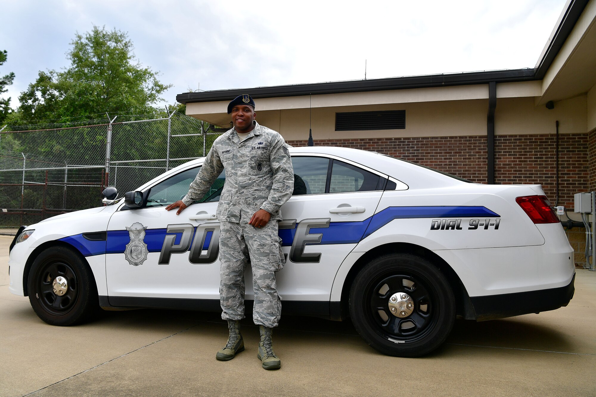 A man in the ABU stands in front of a police car.