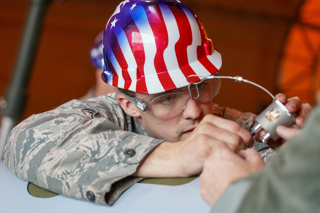 An airman wearing a hard hat focuses on building a bomb unit.